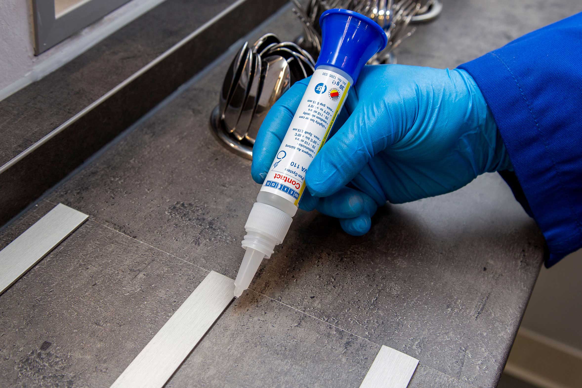 Landingpage_Einsatzgebiete_Lebensmittel_VA110_Bild_1 schmale Metallstreifen werden mit Weicon Sekundenkleber auf eine Armatur geklebt