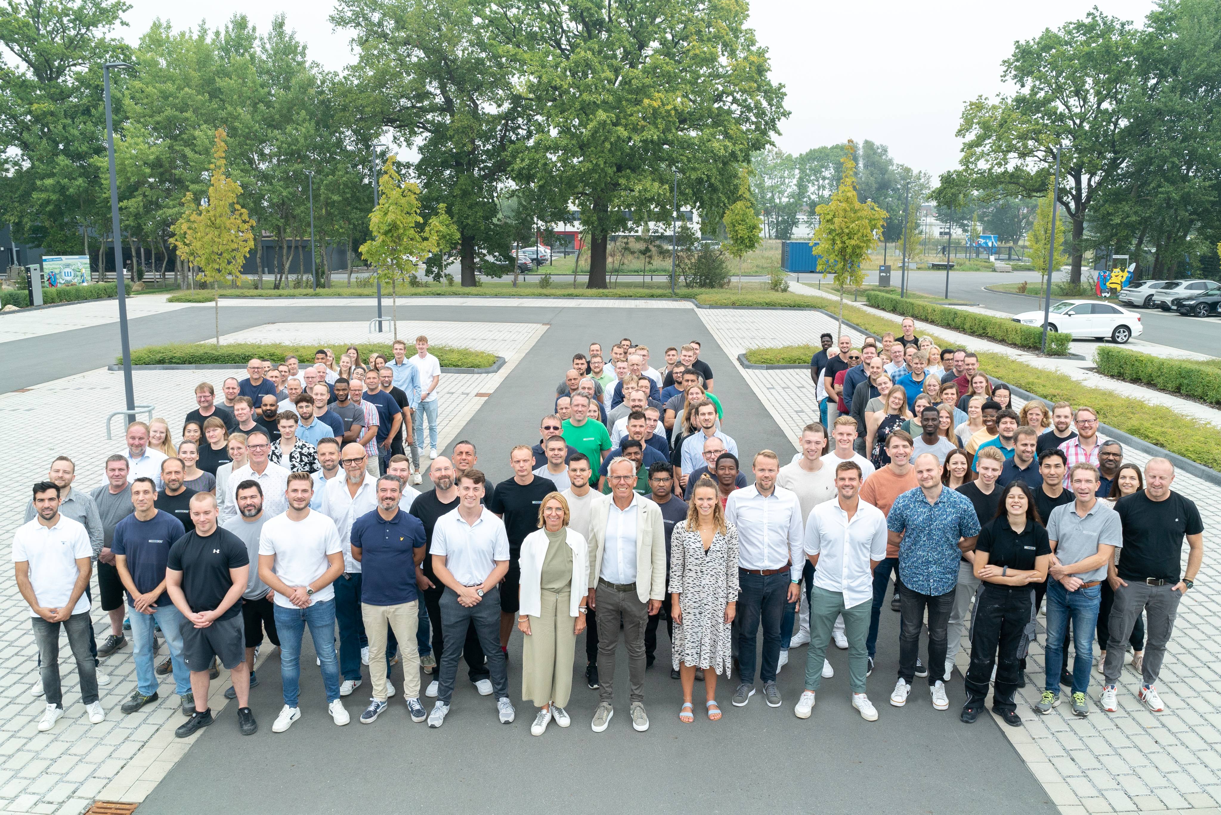 Viele Menschen stehen für ein Gruppenbild als ein W zusammen