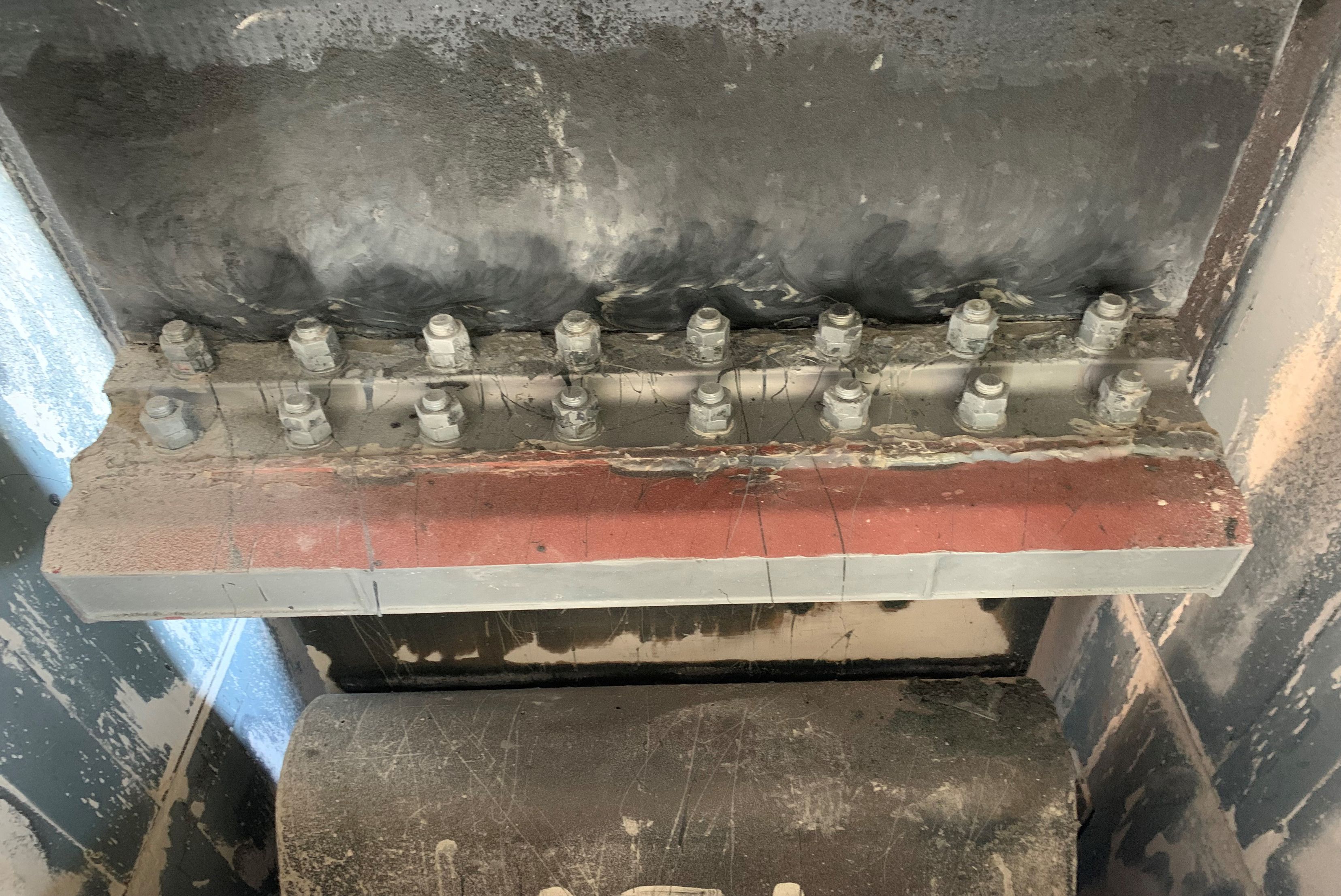 Una connessione a flangia industriale con due file sovrapposte di bulloni e dadi esagonali che uniscono saldamente componenti metallici e in gomma di un impianto.