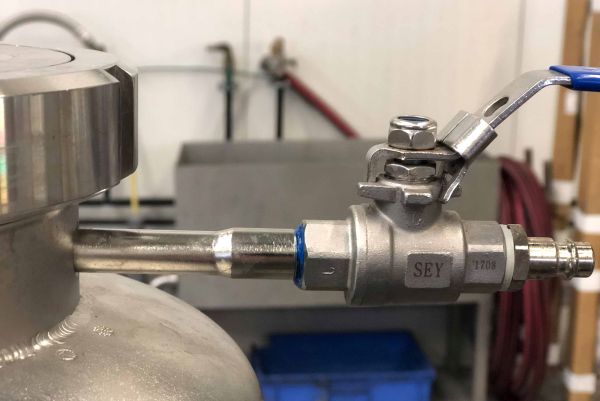 Vanne à bille en acier inoxydable fixée sur la conduite d'un réservoir métallique.