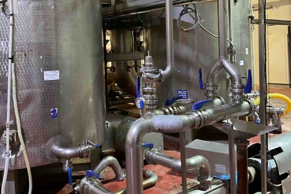 Installation industrielle de cuves en acier inoxydable avec un réseau complexe de tuyauteries et de vannes à poignée bleue.