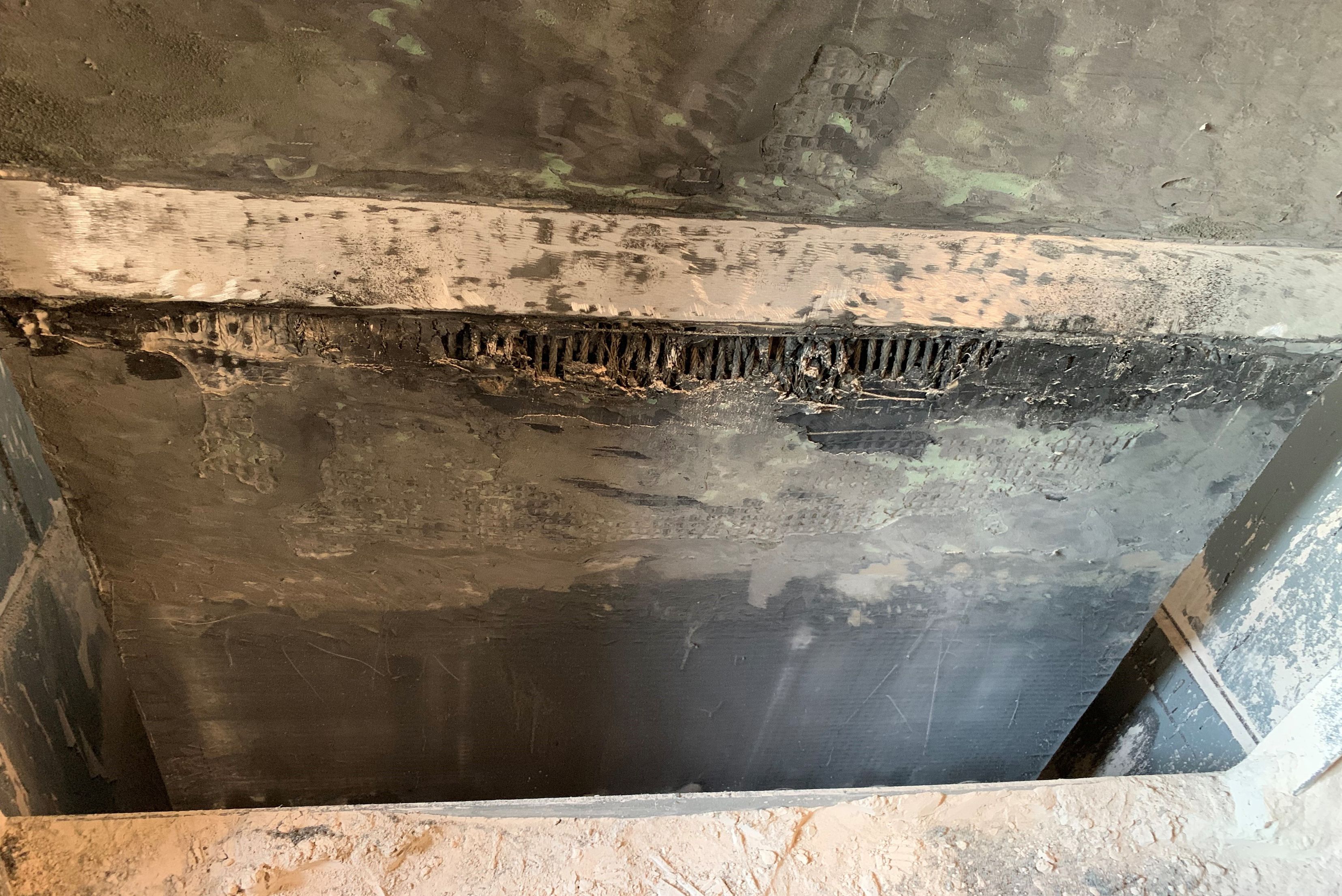 Una superficie in calcestruzzo o pietra ruvida e danneggiata, caratterizzata da texture irregolari e scure dislivelli nella parte superiore.