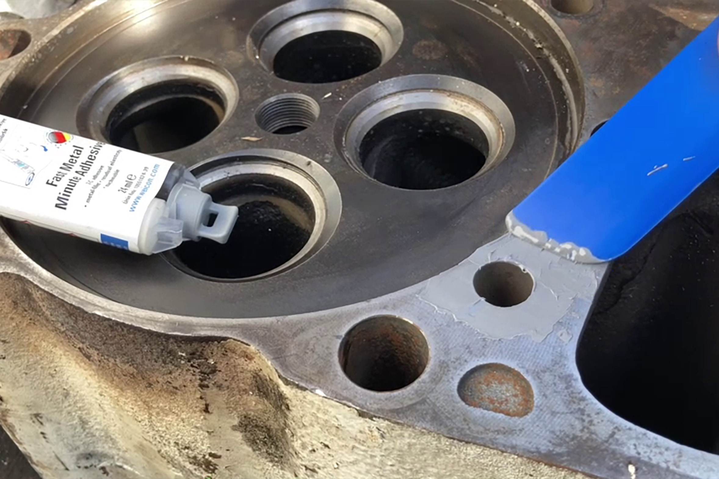 WEICON-Fast-Metal-Minutenkleber_Reparatur-des- Zylinderblocks-eines-Schiffsmotors Ein Motorblock mit zylindrischen Löchern. Darauf liegt der Weicon Fast-Metal-Minutenkleber.