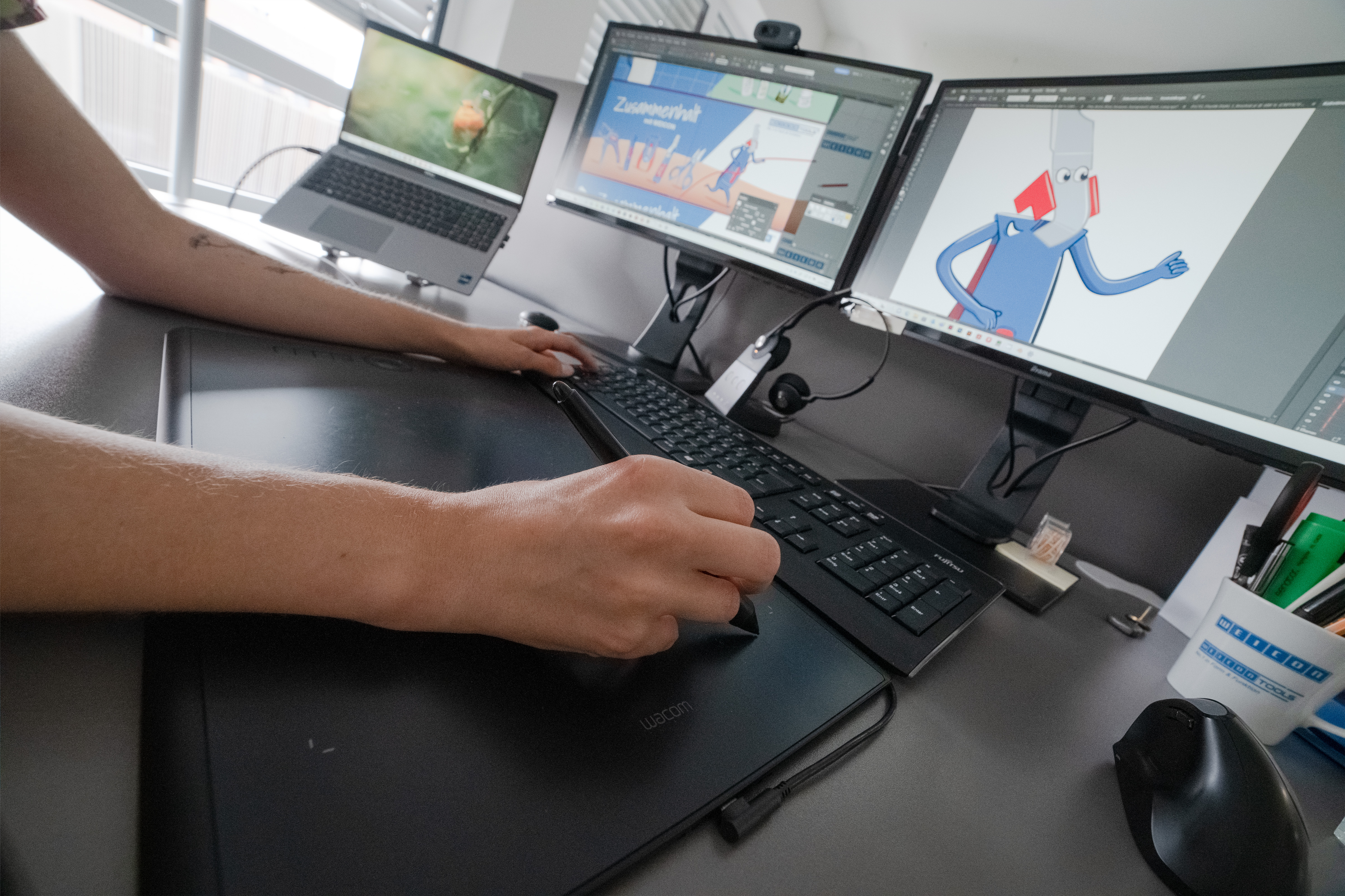 Zwei Hände, die an einem Computer eine Grafik bearbeiten
